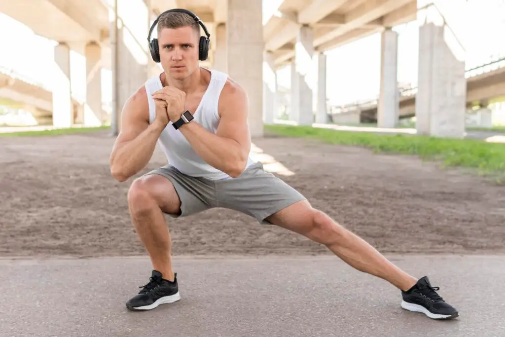 long shot athletic man stretching Man doing exercise in a gym wearing sportswear, focusing on fitness and strength training.