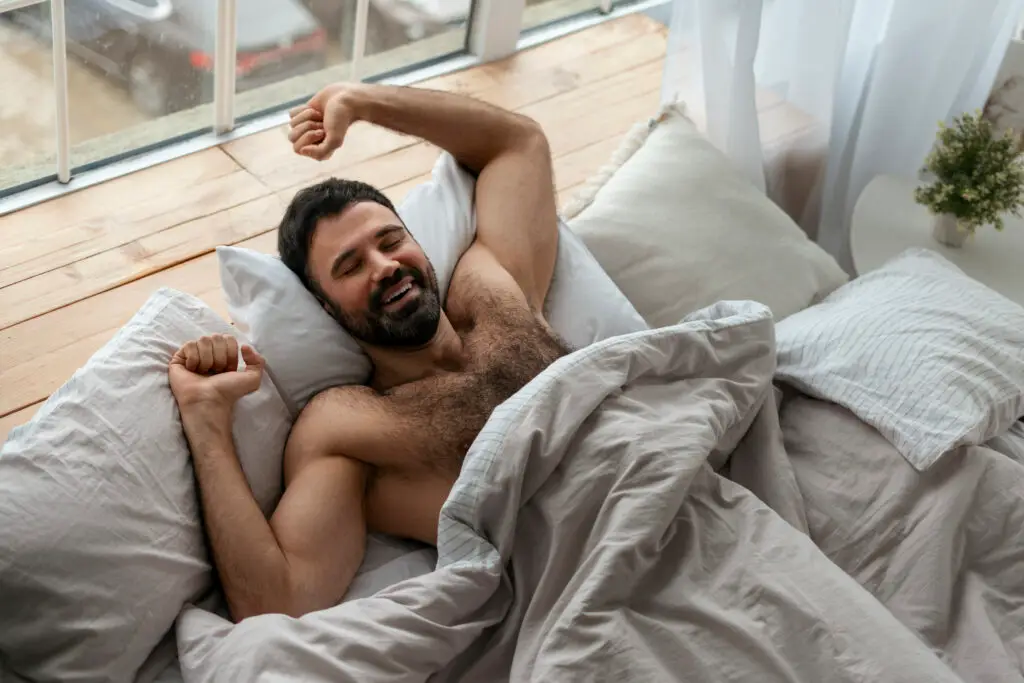 medium shot man laying bed Man sleeping peacefully on a bed, resting comfortably for better health and relaxation.