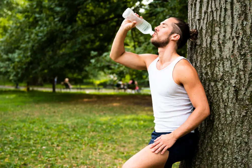 side view runner drinking water fit man